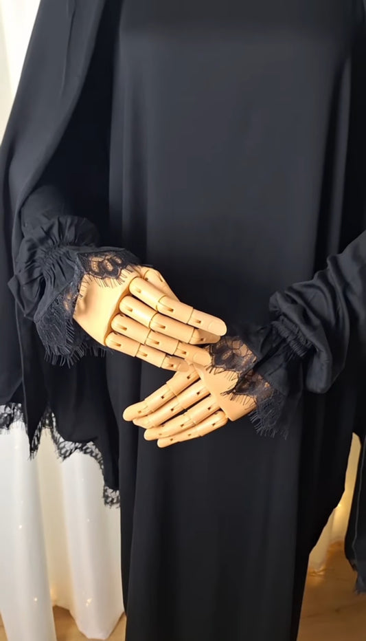 Detailaufnahme der Ärmel mit fein eingearbeiteter Spitze in Schwarz.