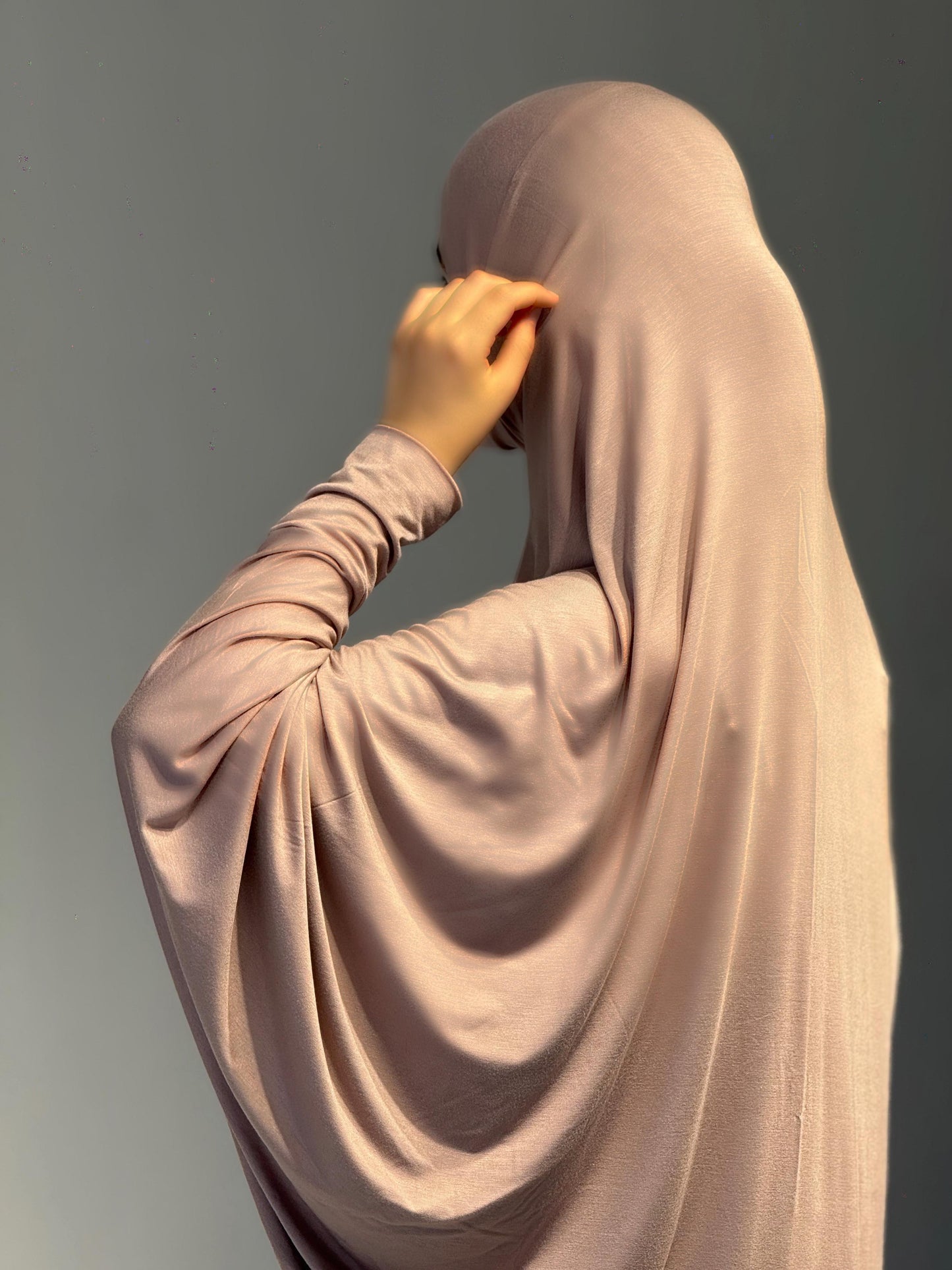 Frau im Jilbab Beige Sahra wendet den Kopf leicht zur Seite, die Rückseite des Outfits zeigt sich weich fließend.