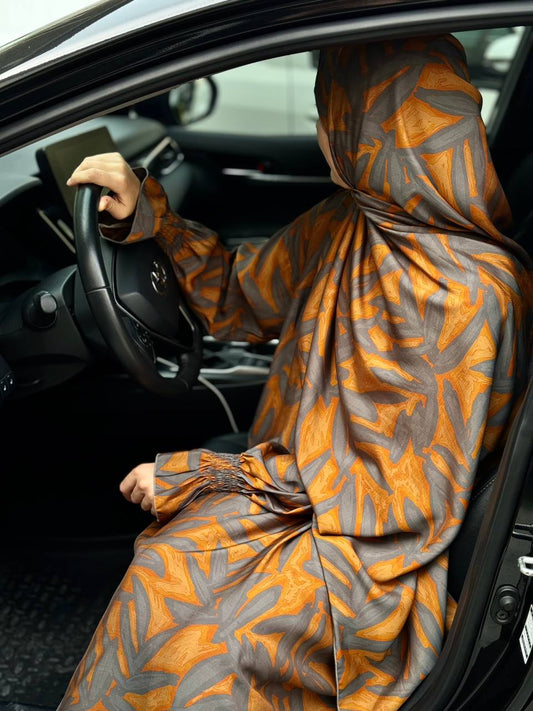 Abaya in Braun-Orange mit Blattmuster, sitzend am Steuer