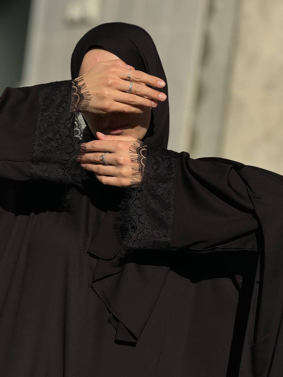 Elegante Vorderansicht der schwarzen Abaya Aswad Noir mit feinen Spitzendetails.