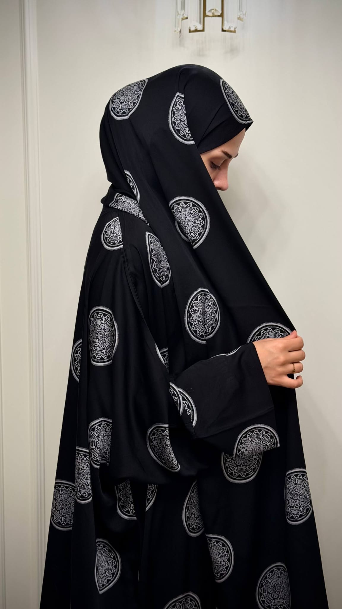 Seitenansicht der schwarzen Butterfly Abaya Mahira mit langem angenähtem Kopftuch und silberfarbenem Ornamentmuster.