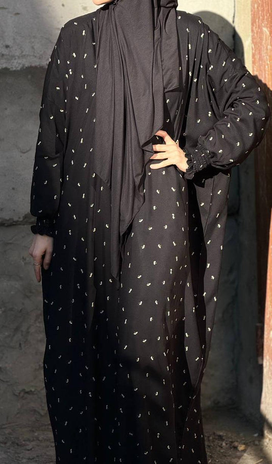 Abaya „Tawhid Noir“ seitlich fotografiert – fließender Viskose-Stoff, integrierter Hijab und dezentes edles Muster.