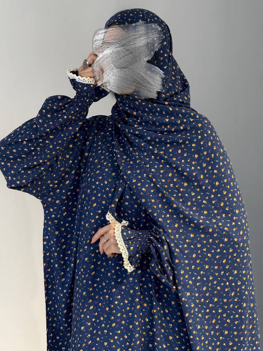 Frontale Pose mit angehobenem Arm, das Gesicht  leicht verhüllt - betont das florale Muster und die praktische Schnittführung