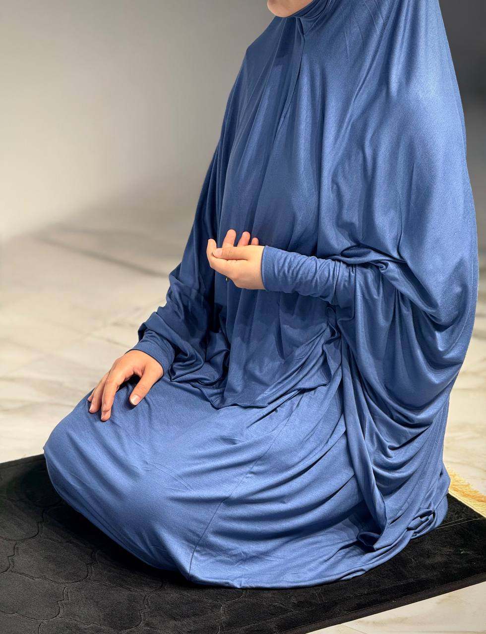 Frau im Jilbab Azraq Ocean in sitzender Position, Hände auf den Oberschenkeln, weicher Jersey-Stoff in sattem Blau.