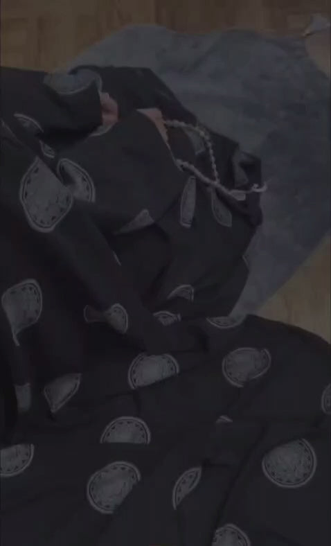 Schwarzes Butterfly Abaya Set Mahira beim Gebet mit locker fallendem Stoff, weiten Ärmeln und silberfarbenen Mustern.